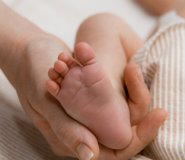 Hand holding infant foot Hand holding infant foot